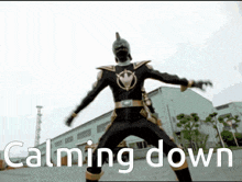 a man in a black and gold costume is standing in front of a building with the words calming down below him