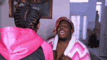 a man in a pink robe and a woman in a pink hoodie are laughing together .
