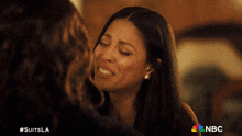 a woman hugging another woman with the nbc logo in the background