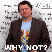 a man in a suit stands in front of a white board that says " why not " on it