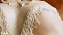 a close up of a white cake with lace and a bow
