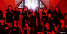a group of girls are posing for a picture in front of a window in a dark room .