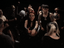 a group of people are dancing in a dark room with a woman wearing a choker that says ' x ' on it