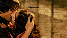 a man is kissing a woman who is wearing a mask on her face .
