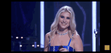 a woman in a blue dress is smiling on a stage