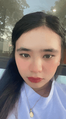 a young woman wearing a white shirt and a gold necklace