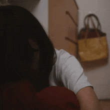 a woman is sitting in front of a purse hanging on a wall