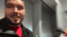 a man with a beard is smiling in a blurry photo with a red arrow pointing to the left
