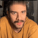 a man with a beard and mustache wearing a yellow shirt