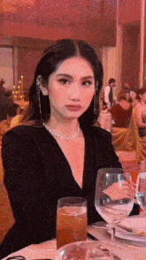 a woman is sitting at a table with a glass of wine in front of her .
