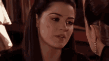 a woman is talking to another woman in a room while wearing earrings .