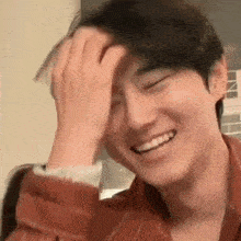 a close up of a man holding his hand to his forehead while smiling .