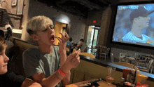 two young boys eating chips in front of a large screen showing a baseball game being played