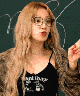 a blonde woman wearing glasses and a black tank top that says holiday