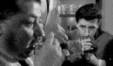 a group of men are drinking wine in a black and white photo .