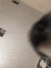 a person is standing in a room with a white wall and a black object in the foreground .