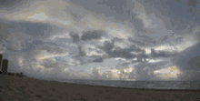 a beach with a cloudy sky and a few buildings in the distance