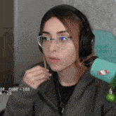 a woman wearing glasses and headphones has a cube of 100 on her sleeve