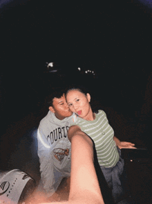 a man wearing a courts shirt kisses a woman