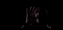 a person with a bloody hand covering their face in the dark