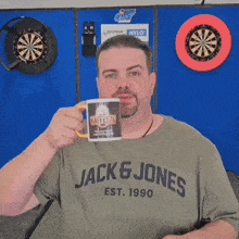 a man in a jack & jones shirt is holding a mug