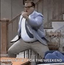 a man in a suit and tie is kneeling down on a couch in a living room .