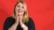 a woman applauds in front of a red background with the words yay