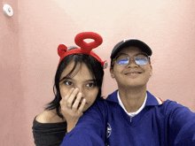 a man and a woman are posing for a picture and the woman is wearing a headband with a red 8 on it