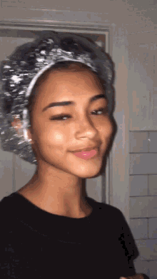 a young woman wearing a plastic shower cap looks at the camera