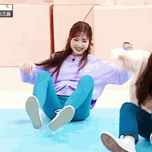 a girl in a purple sweater sits on the floor
