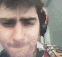 a close up of a man wearing headphones making a funny face