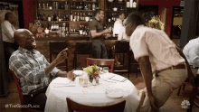 two men are sitting at a table in a restaurant and talking .