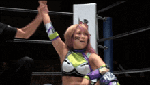 a woman in a wrestling ring holds up her hand in the air