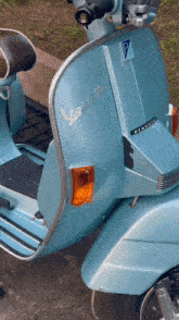 a light blue vespa scooter is parked on a sidewalk