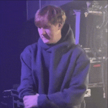a young man wearing a purple hoodie is standing in front of a purple background .
