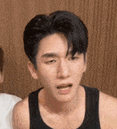 a close up of a man making a funny face while wearing a tank top .