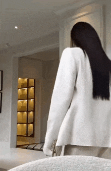 a woman in a white jacket is standing in a room with a chair .