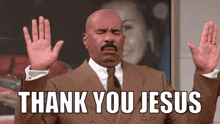 a man in a suit and tie is holding his hands up in the air and saying `` thank you jesus '' .