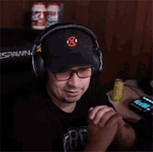 a man wearing headphones and a hat is playing a video game while holding a controller .