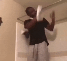 a man is holding a roll of toilet paper while standing in a bathroom .