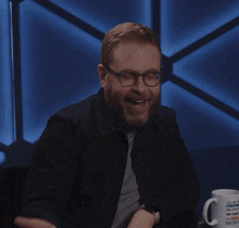 a man wearing glasses holds his hands to his face in front of a mug that says i 'm on my phone
