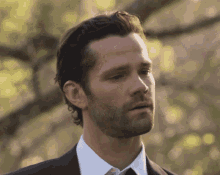 a man with a beard wearing a black suit and white shirt