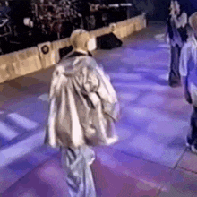 a group of people are dancing on a stage in a purple room .
