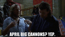 two men are talking to each other in a dark room and the words april big cannons yep are written on the screen .