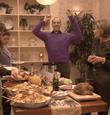 a man in a purple sweater stands in front of a buffet table