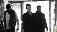 a black and white photo of a group of men with a bottle of lemonade in the background