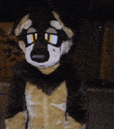a furry dog costume with yellow eyes is standing in front of a wooden fence