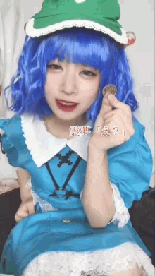a girl with blue hair is holding a coin in her hand