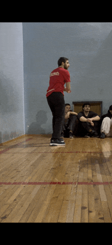 a man in a red shirt that says ' georgia ' on it is standing on a wooden floor