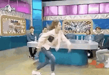 a woman is dancing on a stage in front of a crowd of people sitting at tables .